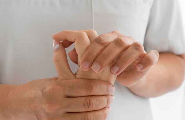 A patient examining hand joints during a consultation at a Rheumatology Hospital in Sharjah.