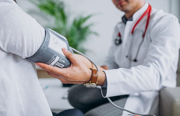 A doctor measuring a patient's blood pressure during a routine checkup at an Internal Medicine Hospital in Sharjah.