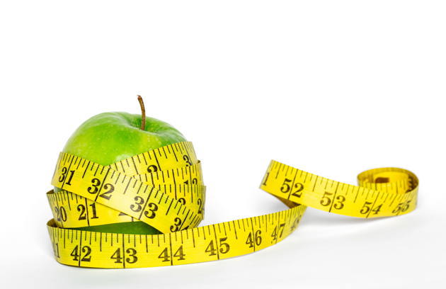 A measuring tape wrapped around an apple symbolizing healthy lifestyle and dietary counseling at a Dietitian Hospital in Sharjah.