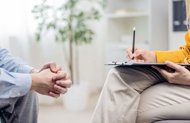 A mental health professional taking notes during a counseling session as part of comprehensive Psychiatry Services in Sharjah.