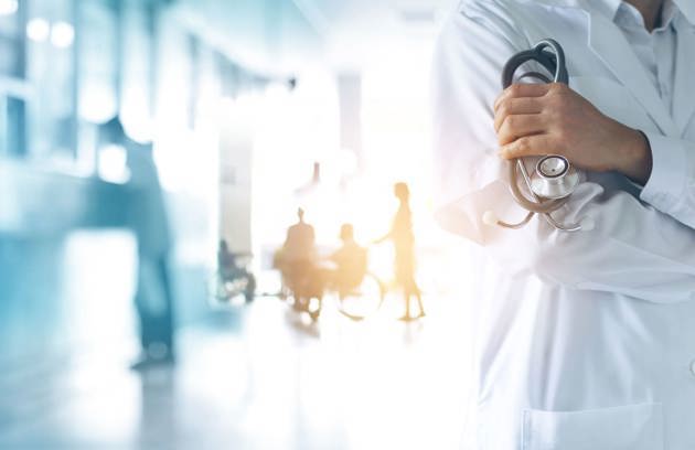 A doctor holding a stethoscope in a hospital corridor, representing professional care for General Surgery in Sharjah